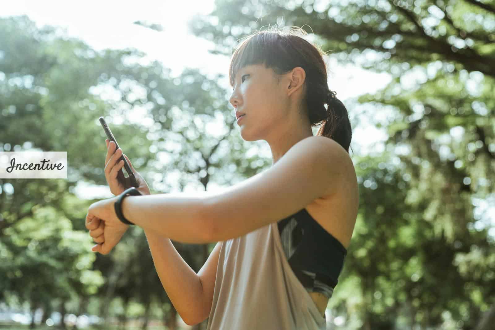 Young Asian woman using devices for fitness in park