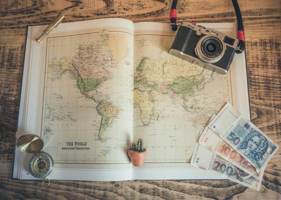 Mapa, cámara de fotos y billetes sobre una mesa al planificar un viaje
